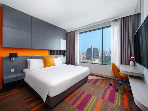 a hotel room with a large bed and a desk at Mercure Bangkok Siam in Bangkok