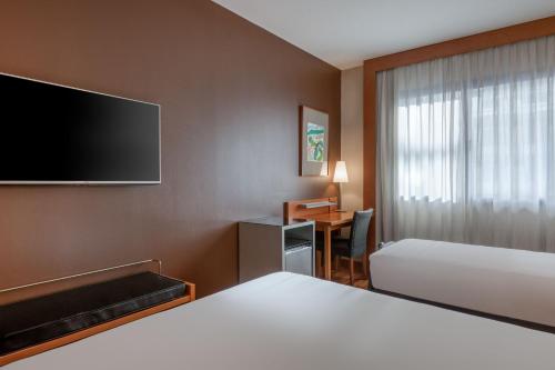 a hotel room with a bed and a desk and a tv at AC Hotel León San Antonio by Marriott in León
