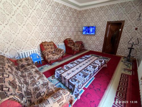 a bedroom with a bed and chairs and a tv at Sezam in Bukhara