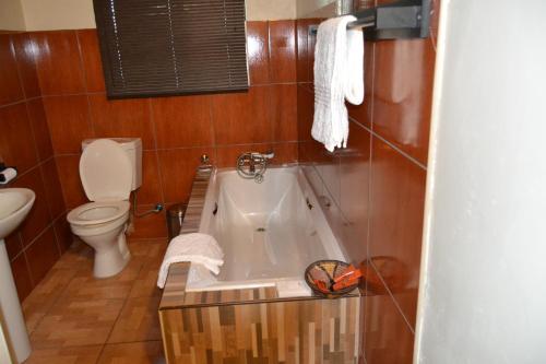 a bathroom with a bath tub and a toilet at Chobe Sunset Chalets in Lesoma