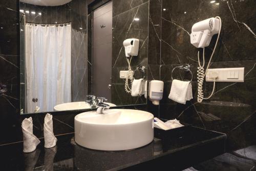 un bagno con lavandino e due telefoni appesi al muro di Hotel Pal Heights a Bhubaneshwar