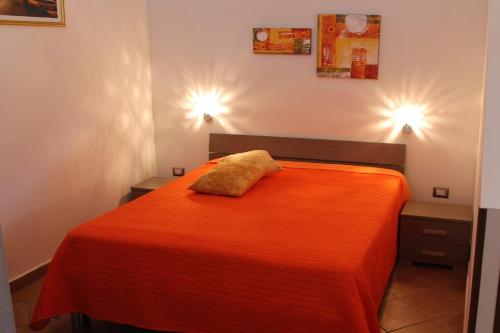 1 dormitorio con 1 cama con colcha de color naranja en Monolocale Letizia en Porto Cesareo