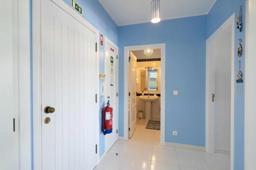 pasillo con paredes azules y baño con extintor de incendios en Feel The Ocean Apartment Praia do Cabedelo, en Viana do Castelo