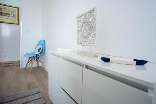 een wit aanrecht met een blauwe stoel in een kamer bij Olhos d'Água - Penthouse in Nazaré