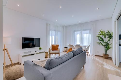 a living room with a gray couch and a tv at FormosaTavira Seaview @Homesbyfc in Tavira