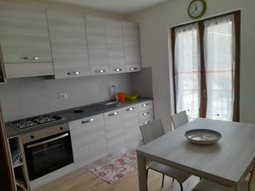 een keuken met witte kasten en een tafel en een eetkamer bij Casa Firmina Appartamento Santa Maria Maggiore in Santa Maria Maggiore