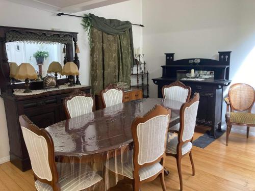 comedor con mesa, sillas y espejo en The Old Station Masters House, en Maryborough