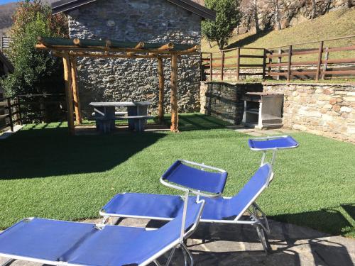 two blue chairs and a picnic table in a yard at Chalet Buonriposo in Cremia