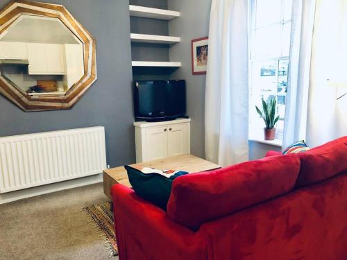 - un canapé rouge dans le salon avec un miroir dans l'établissement Lido's View, à Bristol