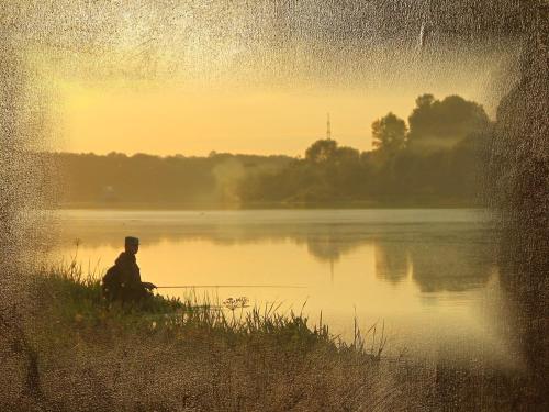 a man sitting on the edge of a lake holding a fishing rod at Burg-Hotel & Hostel Cochem in Cochem