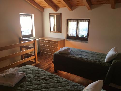 a bedroom with two beds and a dresser and windows at Chalet Buonriposo in Cremia