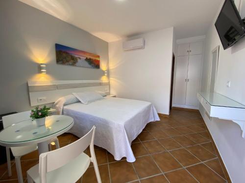 a small room with a bed and a table at Hostal Los Mellizos in Conil de la Frontera