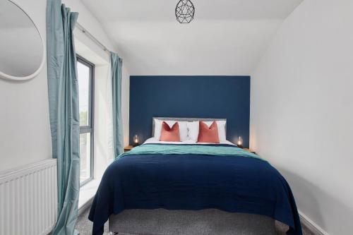 1 dormitorio azul y blanco con 1 cama con almohadas rojas en Fabulous 5 Bed House w Parking, en Mánchester