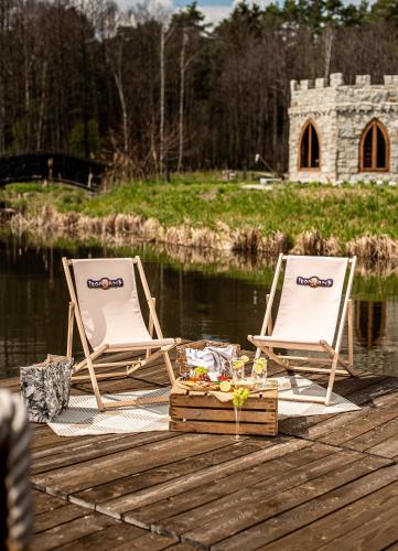 two chairs sitting on a dock next to a body of water at Ironland Roztocze in Ruda Żelazna