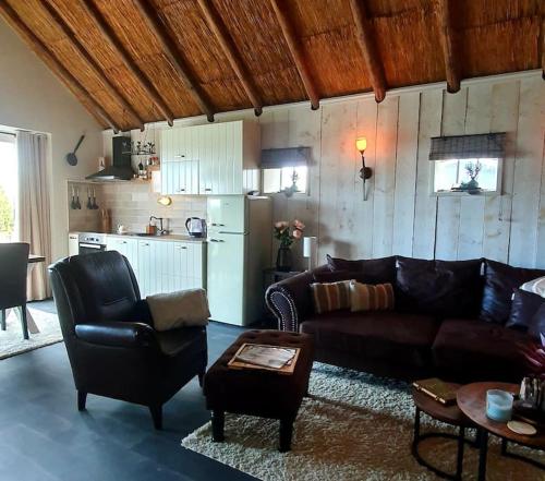 ein Wohnzimmer mit einem Sofa und einer Küche in der Unterkunft The Barn - Aurora Hoeve - loft met jacuzzi in Oldekerk