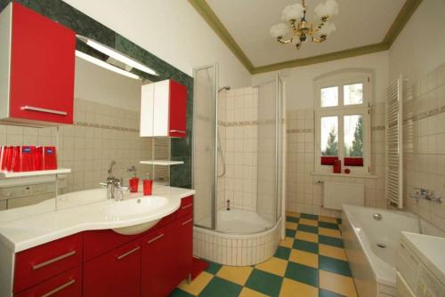 ein Badezimmer mit roten Schränken, einer Badewanne und einem Waschbecken in der Unterkunft Villa Schulenburg in Putbus auf Rügen in Putbus
