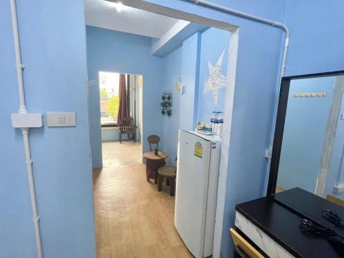 a blue room with a refrigerator and a hallway at Bake Room Hostel in Chiang Mai