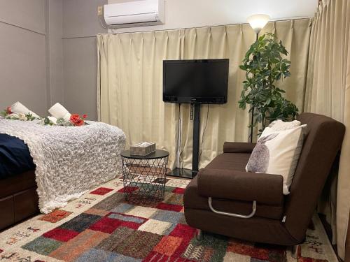 a bedroom with a bed and a chair and a tv at Best Shinjuku Modern Full-furnished Family size Apartment4 ONLY 2min to Shinjuku by Train in Tokyo