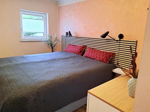 a bedroom with a bed with red pillows and a window at PERO in Eldenburg