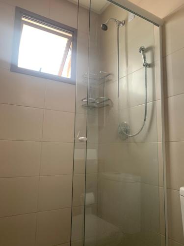 a bathroom with a glass shower with a window at Encantos dos Mares - Apartamento 5 - Balneário Camboriú in Balneário Camboriú