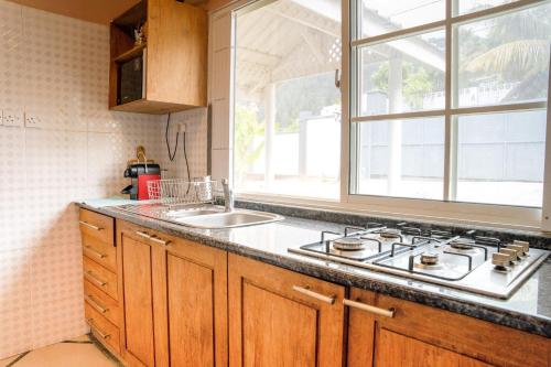 eine Küche mit einem Herd, einem Waschbecken und einem Fenster in der Unterkunft Villa Mille Soleil in Port Glaud