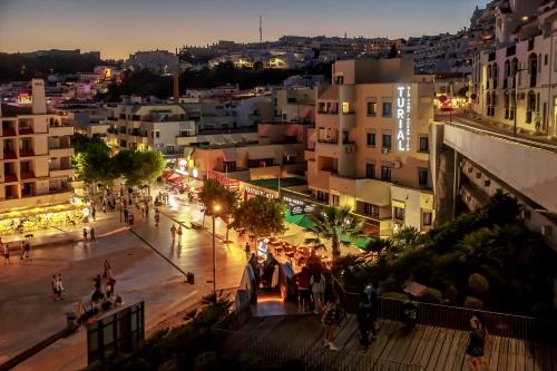 a group of people walking around a city at night at Turial Old Town Ocean View in Albufeira
