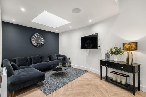 a living room with a couch and a clock on a wall at Princes Wharf, Stylish 2 Bed City Centre Apartment in Newcastle upon Tyne