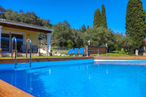 a swimming pool with blue chairs and a house at Green Family Villa in Agios Ioannis