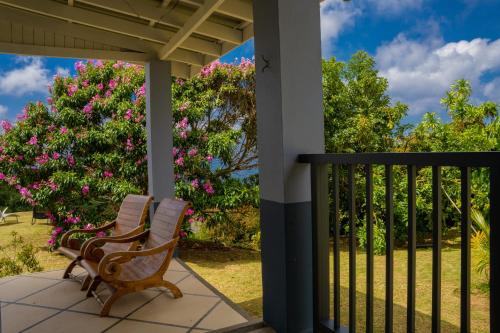 two chairs sitting on a porch with flowers at Villa Mille Soleil in Port Glaud