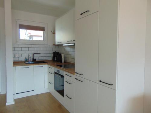 cocina blanca con armarios blancos y ventana en Theos, en Hahnenklee-Bockswiese