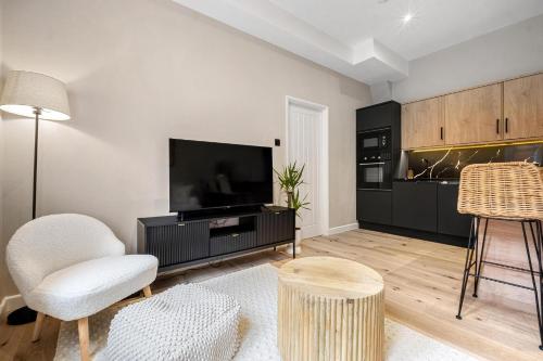 a living room with a flat screen tv and chairs at Stylish 1 Bed City Centre Apartment (Sleeps 4) in Newcastle upon Tyne