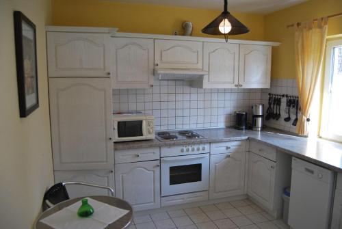 a kitchen with white cabinets and white appliances at Ferienwohnung-Stricker-3-3 in Walkenried