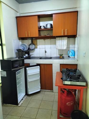 kuchnia z drewnianymi szafkami i czarną lodówką w obiekcie Epic homes w mieście Naivasha