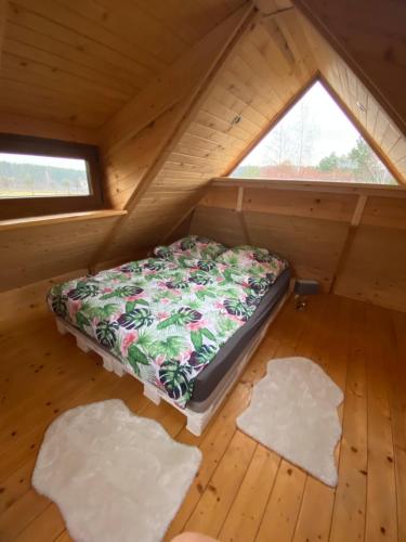 Cama en habitación de madera con 2 almohadas en el suelo en Domek Okale en Kazimierz Dolny