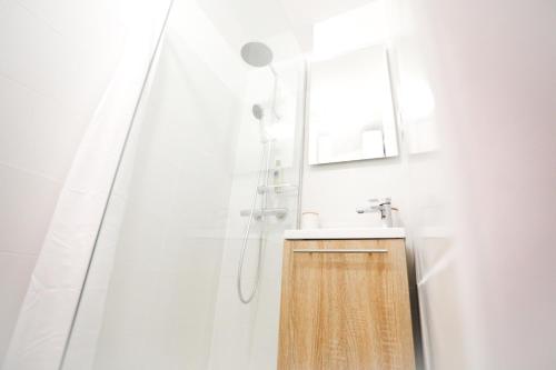 La salle de bains blanche est pourvue d'un lavabo et d'une douche. dans l'établissement Superbe T2 calme & confortable - très bien situé!, à Ajaccio