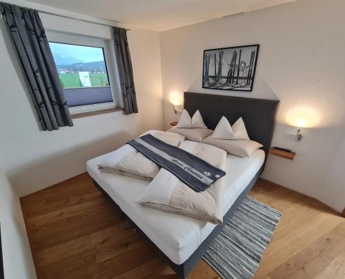 a bedroom with a bed with white pillows and a window at Dahoam by Tani in Oberndorf in Tirol