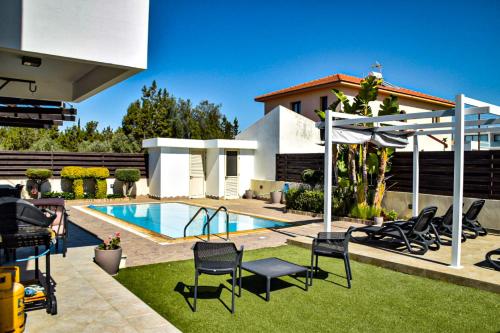a backyard with a swimming pool and chairs and a house at Ilios Villa in Larnaca