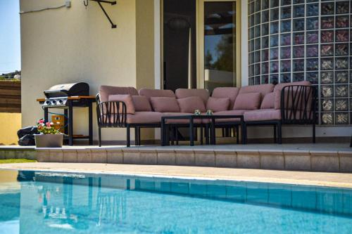 a pool with chairs and a couch next to a house at Ilios Villa in Larnaka