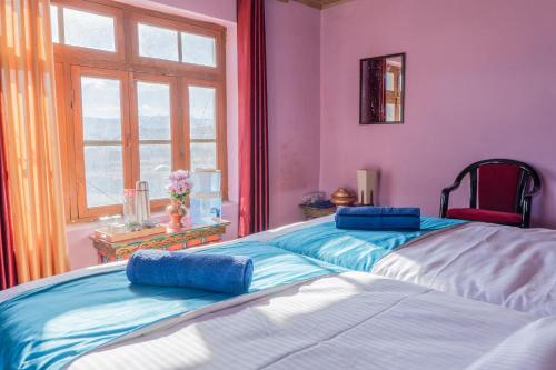two beds in a room with pink and blue at RezangLa Homestay in Chushul