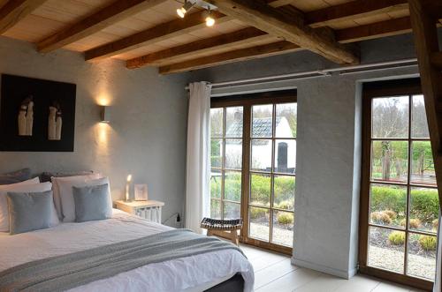 a bedroom with a large bed and large windows at Stee 23 in Hertsberge