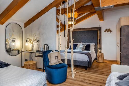 a bedroom with two beds and a blue chair at Hotel Folgarida in Folgarida