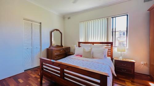 a bedroom with a large bed and a mirror at Carlton 3 beds unit - free parking in Sydney