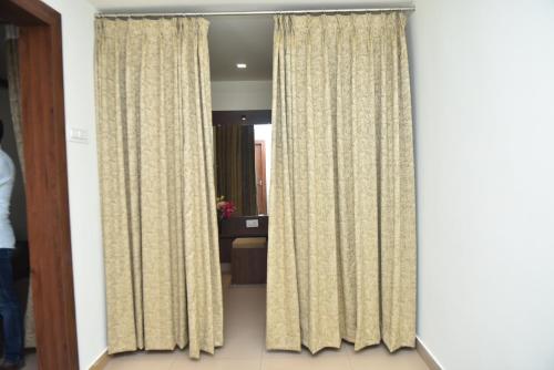 a living room with curtains in a room at M R Residency Dharwad. in Dhārwād