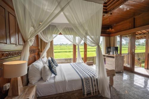a bedroom with a bed with a canopy and a window at Uma Sebatu Villa in Tegalalang