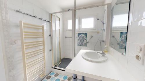 ein weißes Badezimmer mit einem Waschbecken und einem Spiegel in der Unterkunft Plein Sud magnifique vue 180 face mer in Les Bussolleries
