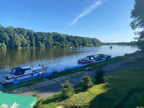 un groupe de bateaux est amarré sur une rivière dans l'établissement Zouw Hausboat Zakotven -pouze ubytovaní, à Roudnice nad Labem