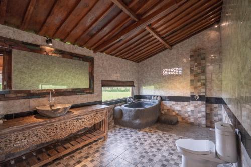a bathroom with a tub and a sink and a toilet at Uma Sebatu Villa in Tegalalang