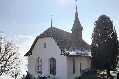 a white church with a steeple on top of it at Königin der Alpen in Beatenberg