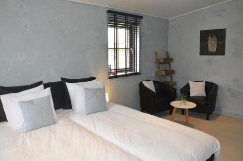 a bedroom with a large white bed and two chairs at Stee 23 in Hertsberge