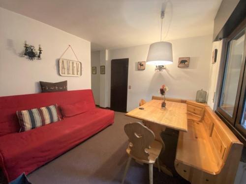 a living room with a red couch and a wooden table at Trilocale Presanella - Serafini in Madonna di Campiglio